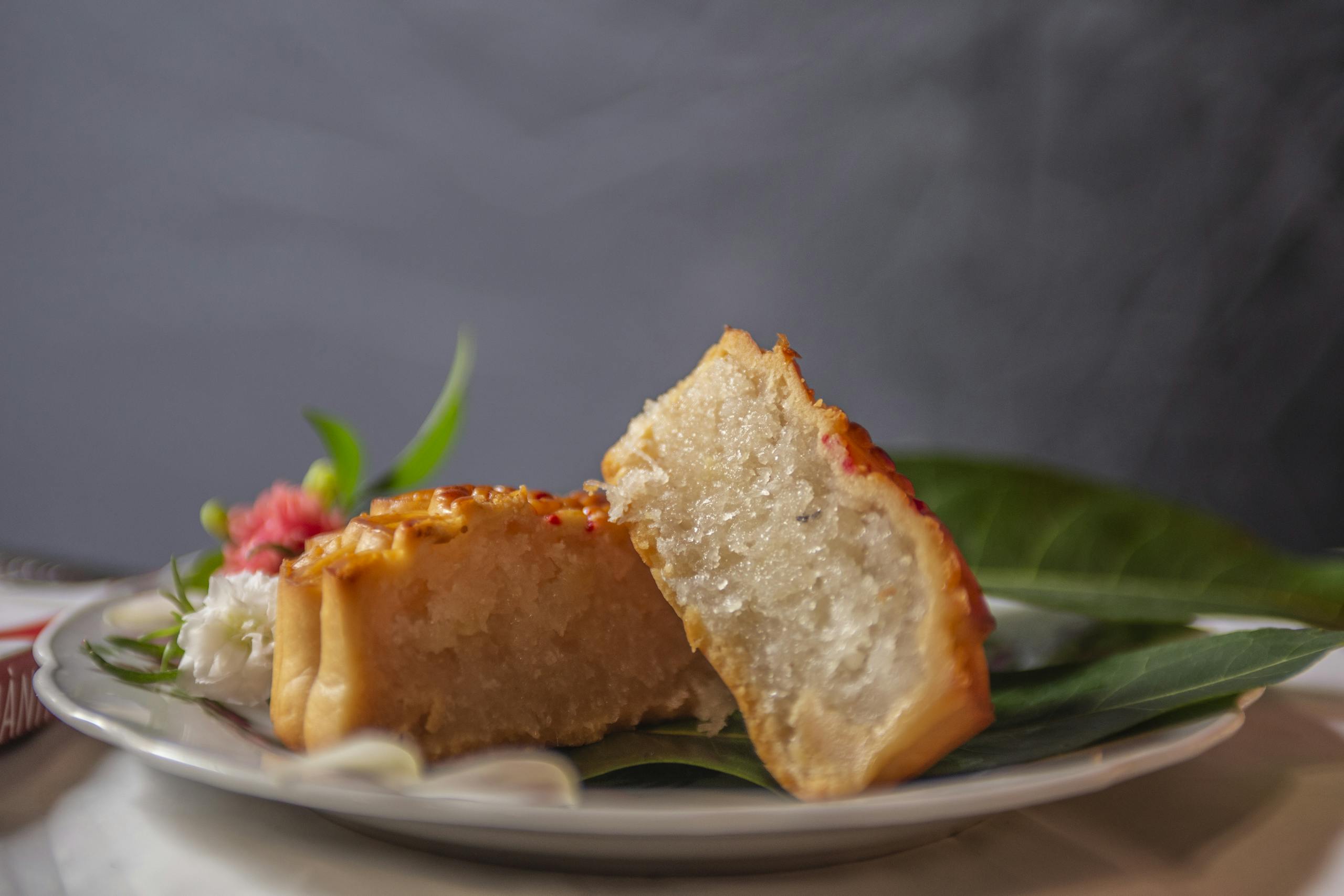 Close-up of a sliced homemade yuca cake on a plate served with leaves, presenting a mouth-watering dessert.
