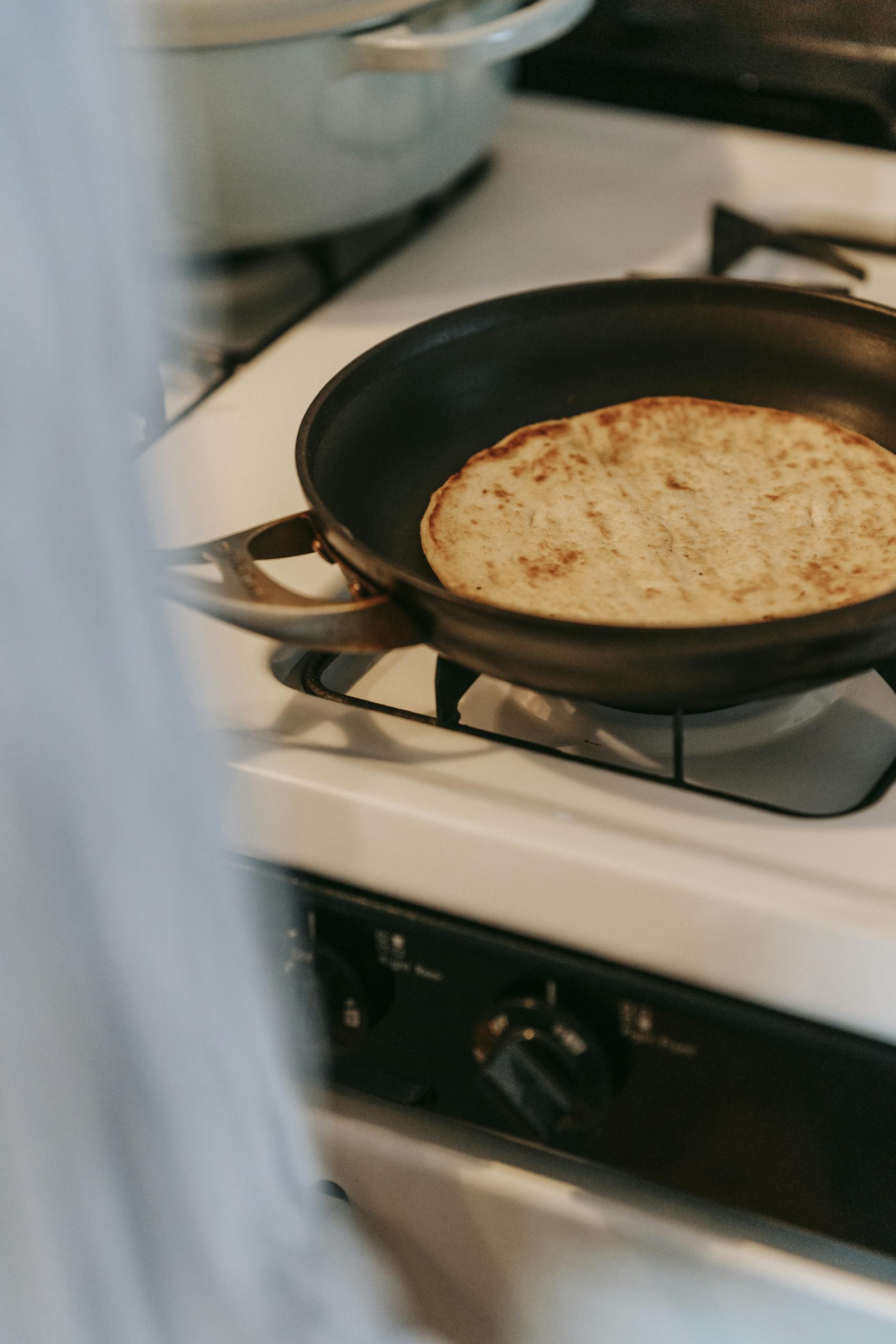 Delicious pita bread being heated on a stove in a frying pan for a tasty breakfast or snack.
