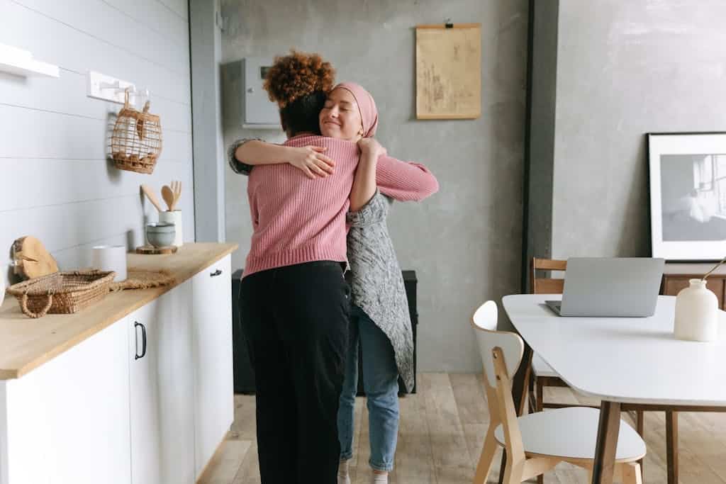 Two women embracing warmly indoors, symbolizing support and friendship.